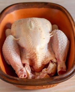 Clean and trimmed whole free-range chicken placed on Romentopf dish