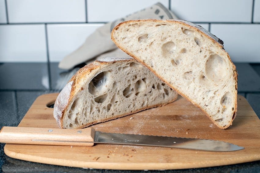 Sourdough loaf cut open on breadboard with bread knife