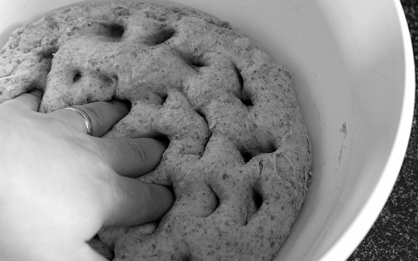 Sourdough bread dough being poked with salt added