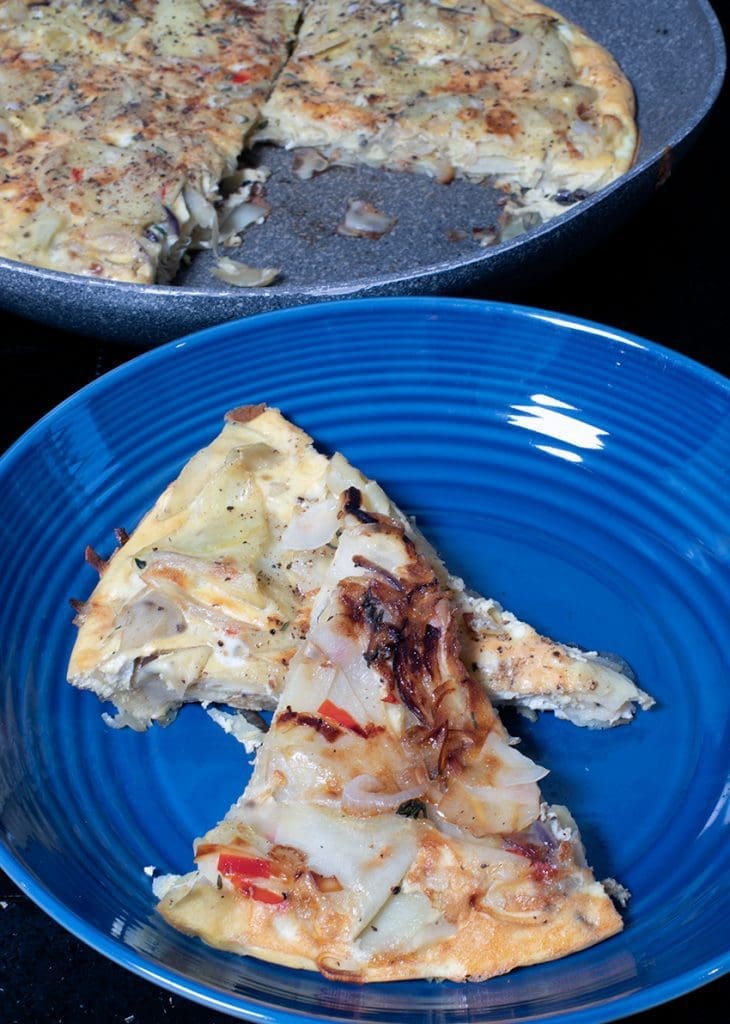 Spanish Tortilla Omelette with Chilli, Thyme, and Garlic sliced with pan in background.